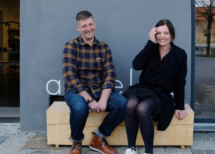 Konrad & Angelika Lipp auf einer Baumstamm-Bank vor dem Atelier 