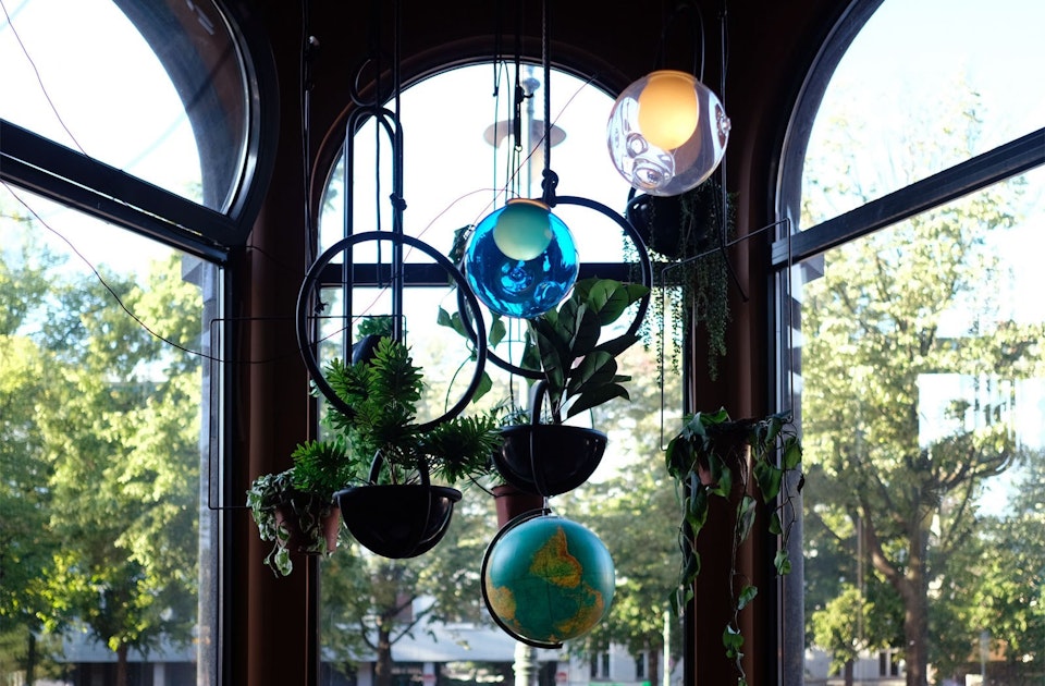 One World. Installation im Erkerfenster: Weltkugel, Leuchten von Bocci, Blumenampeln von Atelier Haussmann