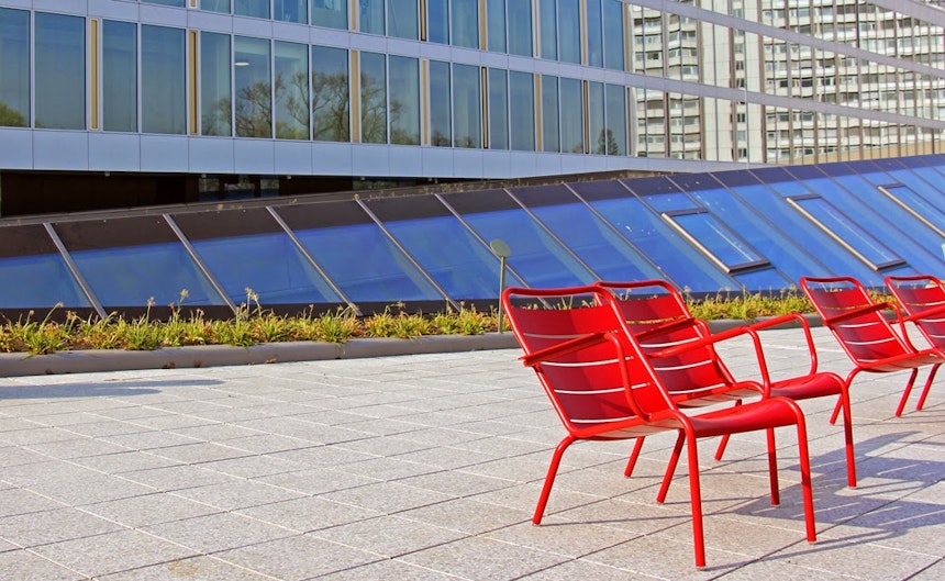 Rote Stühle von 'Fermob' auf der grauen Beton-Terrasse – ein gelungener Kontrast