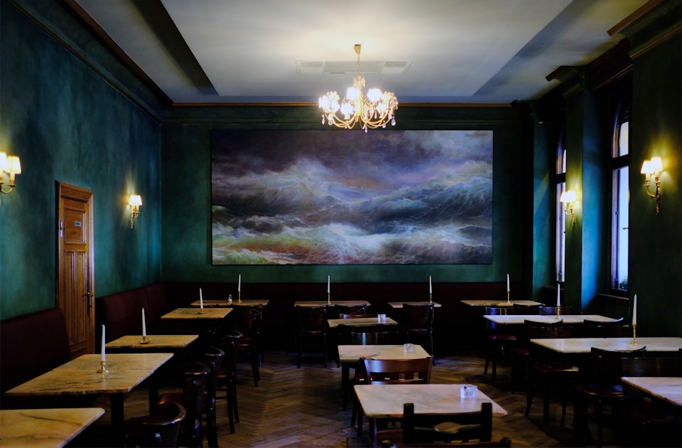 Warmes Petrol, Fischgrat-Parkett und alte Leuchter – Interior im Caféhaus-Stil